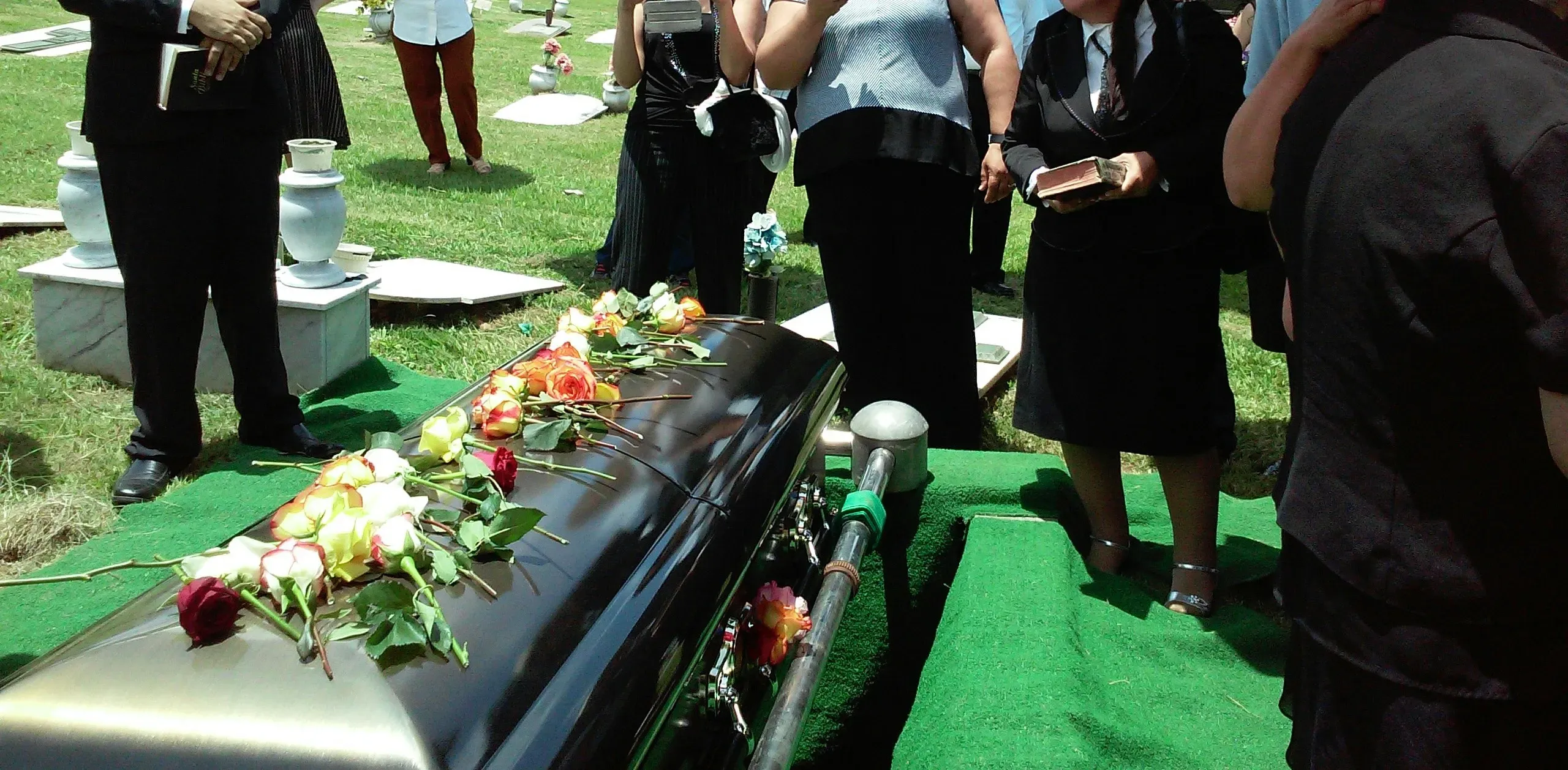 Cueillement et recueillement de la famille autour d'un cercueil fleuri au cimetière.